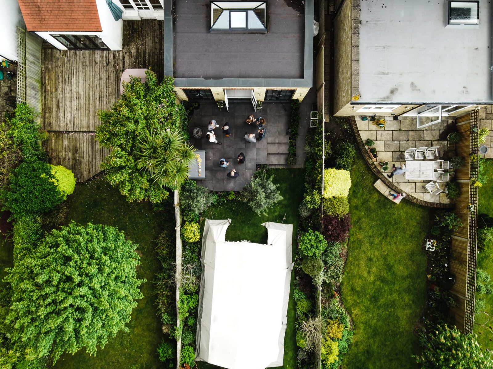Drone shot of backyard gathering in England, showcasing garden and people.